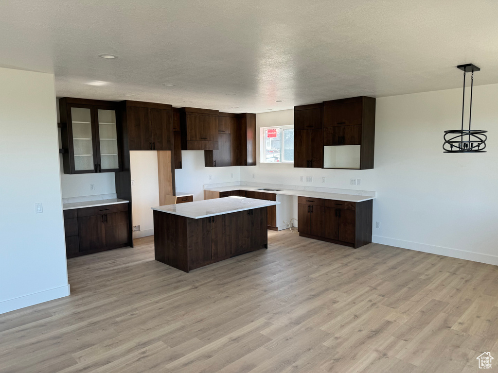 Kitchen featuring a center island, light hardwood / wood-style flooring, dark brown cabinets, and decorative light fixtures