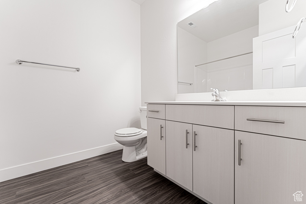 Bathroom with visible vents, toilet, wood finished floors, baseboards, and vanity