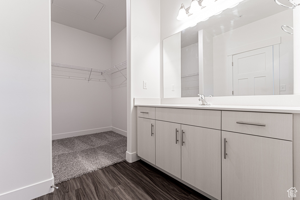 Bathroom with baseboards, vanity, wood finished floors, and a spacious closet