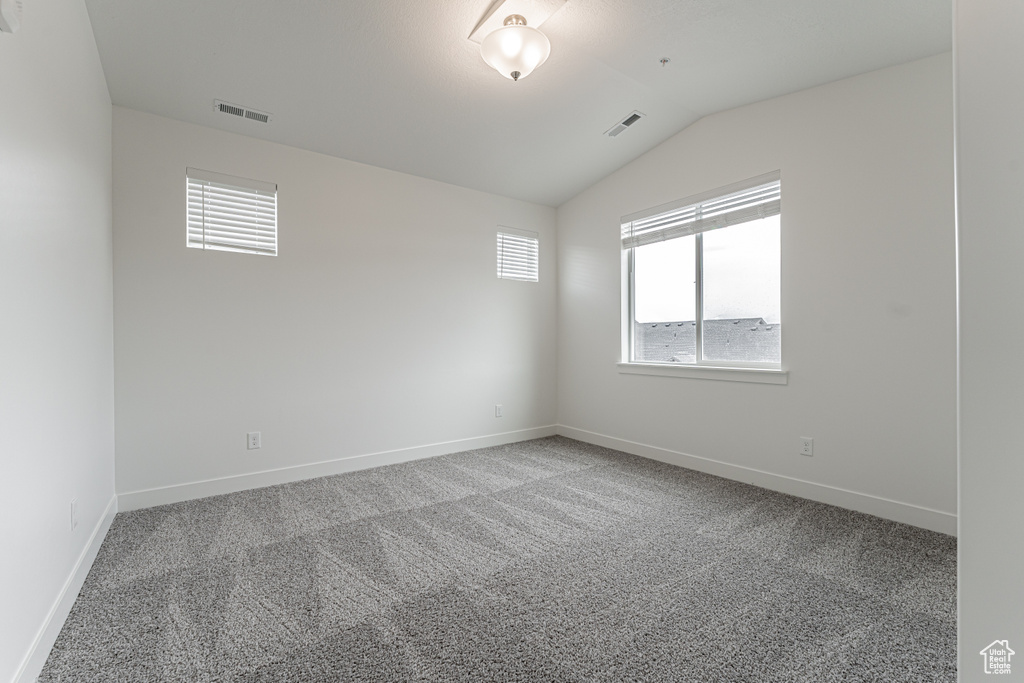 Unfurnished room with lofted ceiling, baseboards, visible vents, and carpet floors