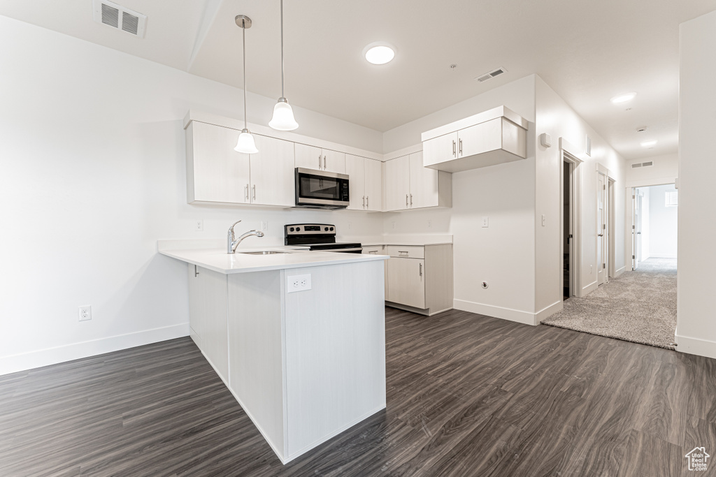 Kitchen with baseboards, visible vents, a peninsula, light countertops, and appliances with stainless steel finishes