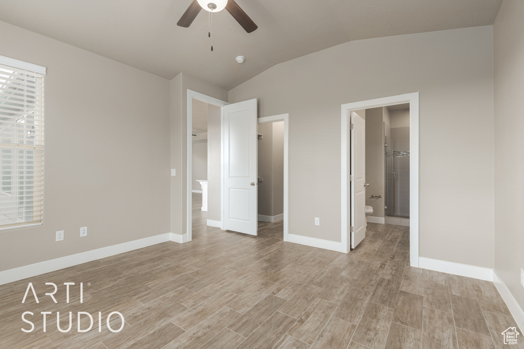 Unfurnished bedroom featuring ensuite bath, lofted ceiling, light wood-type flooring, and ceiling fan