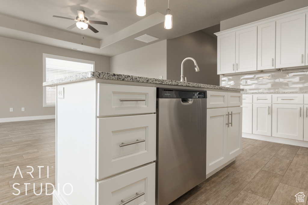 Kitchen with ceiling fan, white cabinetry, stainless steel dishwasher, decorative light fixtures, and light stone counters