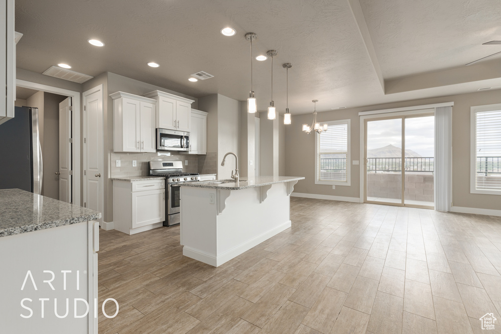 Kitchen with appliances with stainless steel finishes, a chandelier, pendant lighting, and white cabinets