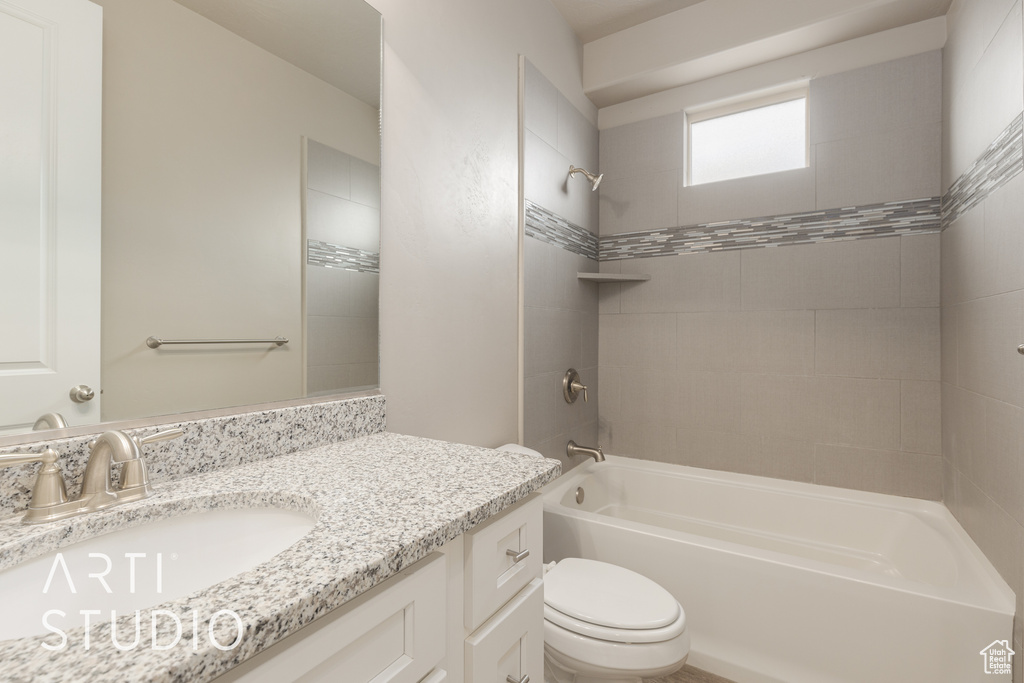 Full bathroom with toilet, tiled shower / bath combo, and vanity