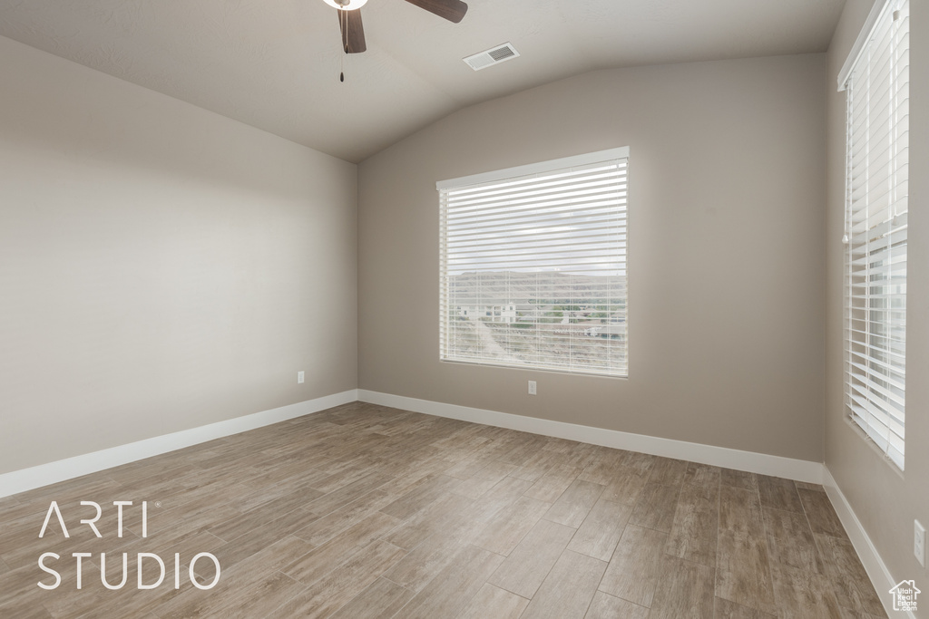 Empty room featuring a wealth of natural light, lofted ceiling, light hardwood / wood-style floors, and ceiling fan