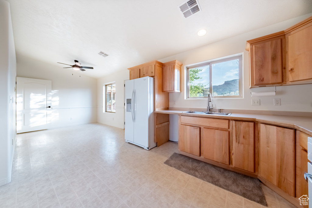 Kitchen featuring ceiling fan, white refrigerator with ice dispenser, and sink