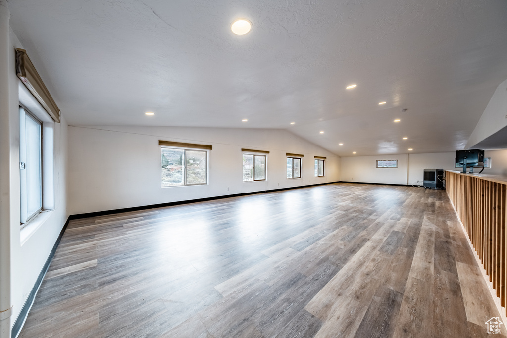 Unfurnished living room featuring light wood-type flooring and lofted ceiling