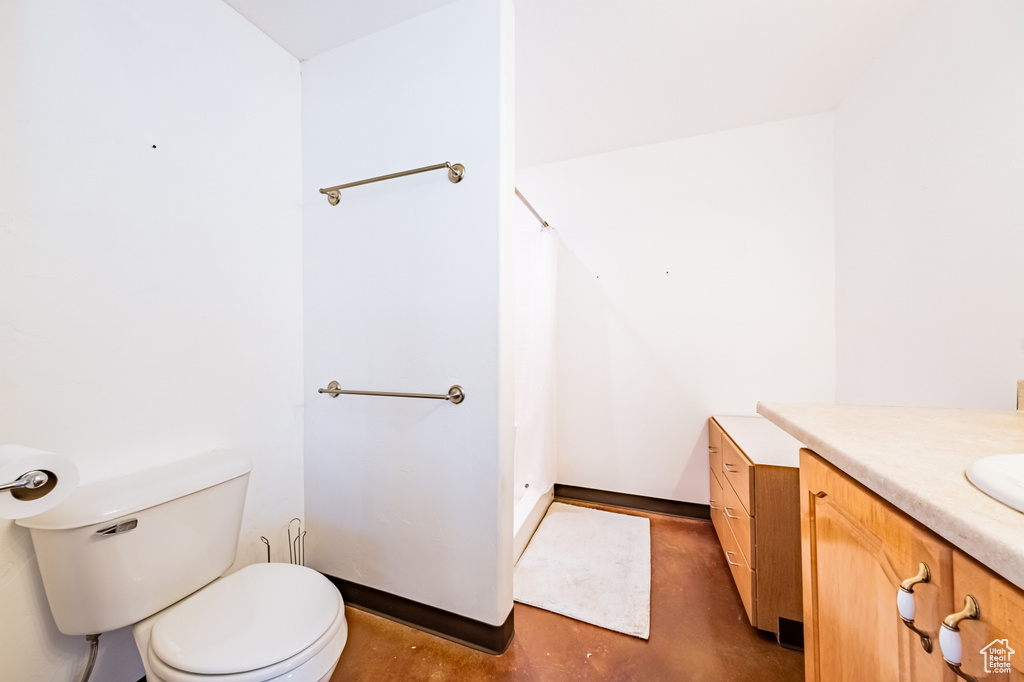 Bathroom with toilet, vanity, and concrete floors