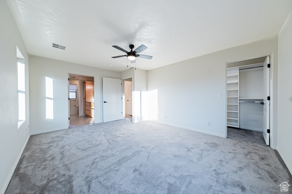 Unfurnished bedroom featuring ensuite bathroom, ceiling fan, a closet, and carpet flooring