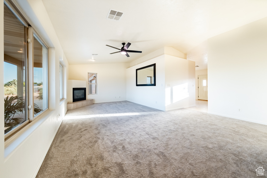 Unfurnished living room with lofted ceiling, ceiling fan, light carpet, and a tile fireplace