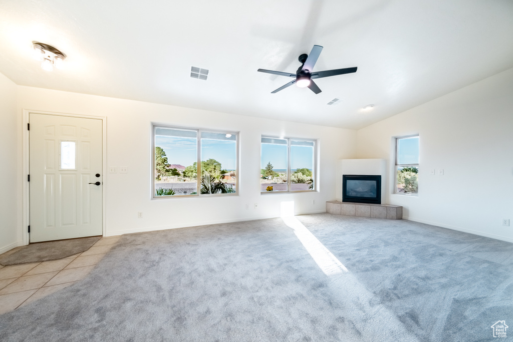 Unfurnished living room with a fireplace, ceiling fan, vaulted ceiling, and light carpet