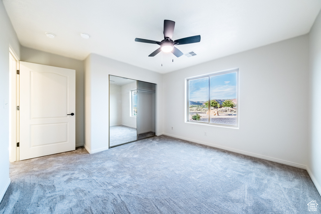 Unfurnished bedroom featuring light carpet, ceiling fan, and a closet