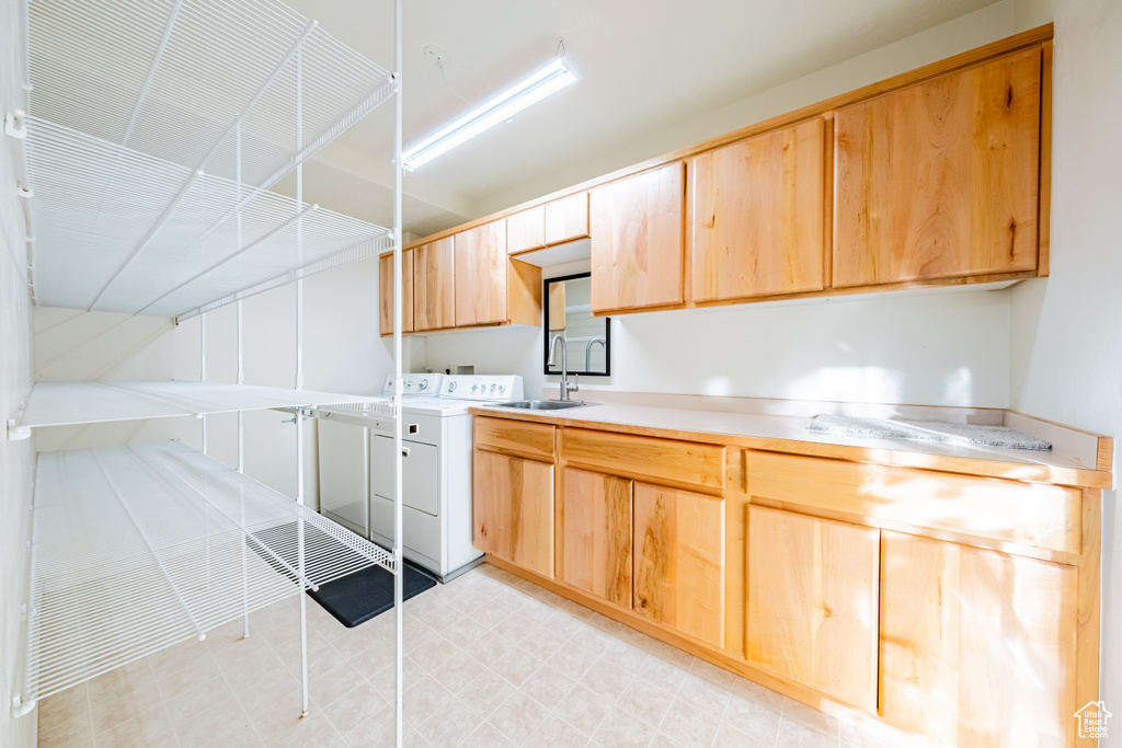 Kitchen with washing machine and clothes dryer, sink, and light brown cabinets