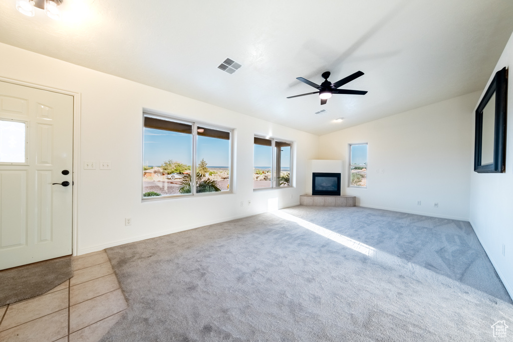 Unfurnished living room featuring ceiling fan, light colored carpet, a fireplace, and lofted ceiling