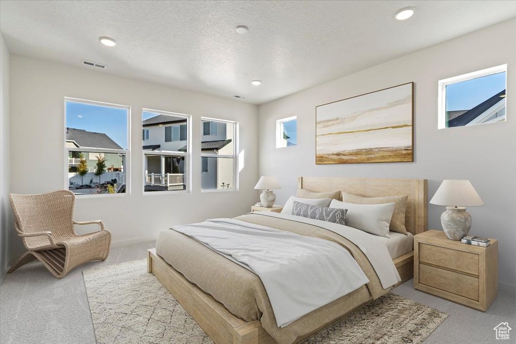 Carpeted bedroom featuring multiple windows and a textured ceiling