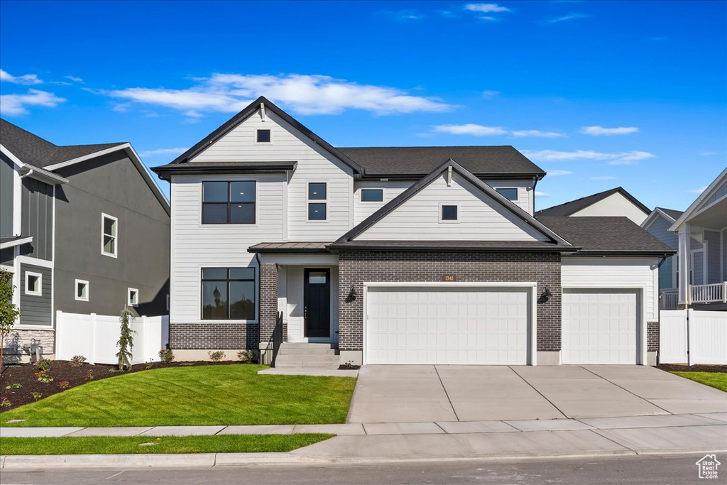 View of front of property featuring a front yard and a garage