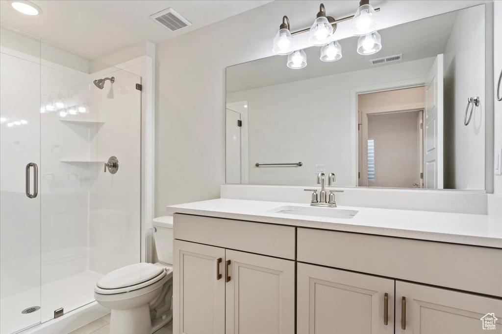 Bathroom featuring vanity, toilet, walk in shower, and tile patterned flooring