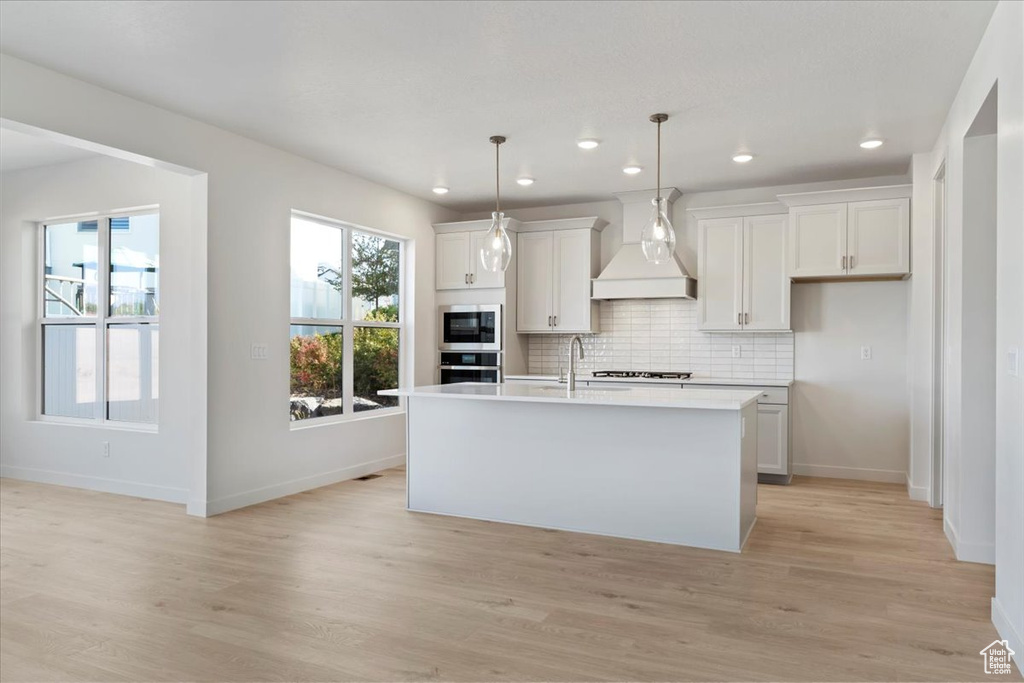 Kitchen with appliances with stainless steel finishes, a healthy amount of sunlight, and an island with sink