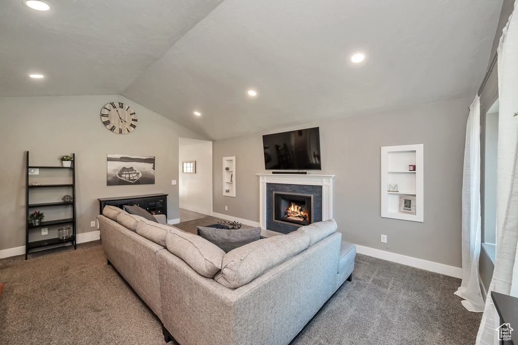 Living room featuring built in features, vaulted ceiling, and dark carpet