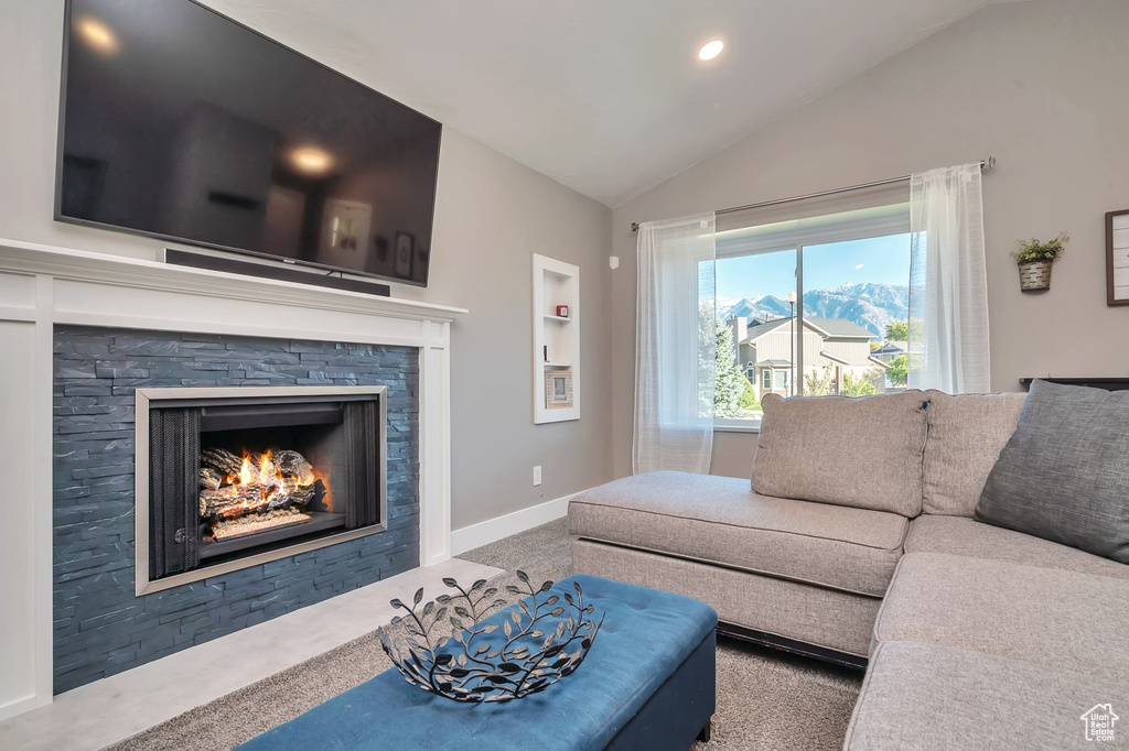 Living room featuring carpet, vaulted ceiling, a stone fireplace, and a mountain view