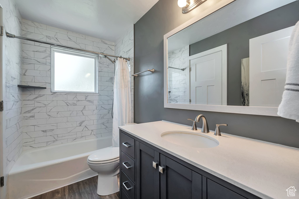 Full bathroom with shower / bath combination with curtain, toilet, vanity, and hardwood / wood-style floors