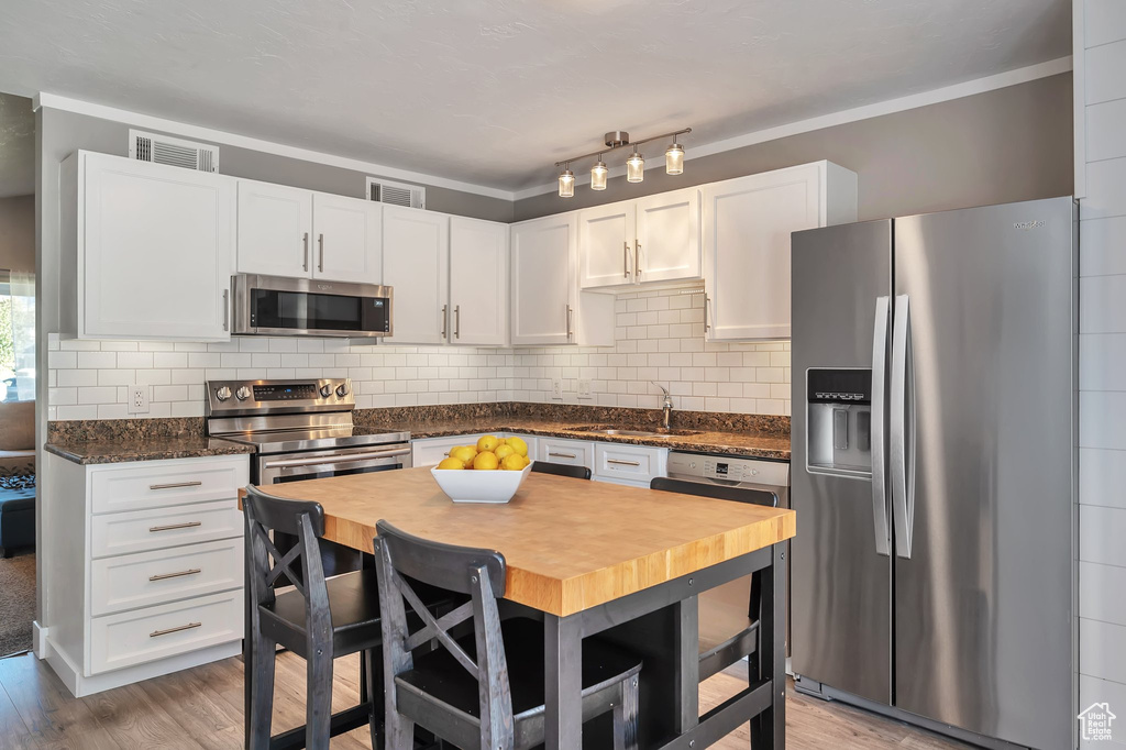 Kitchen featuring sink, appliances with stainless steel finishes, hardwood / wood-style flooring, and white cabinetry