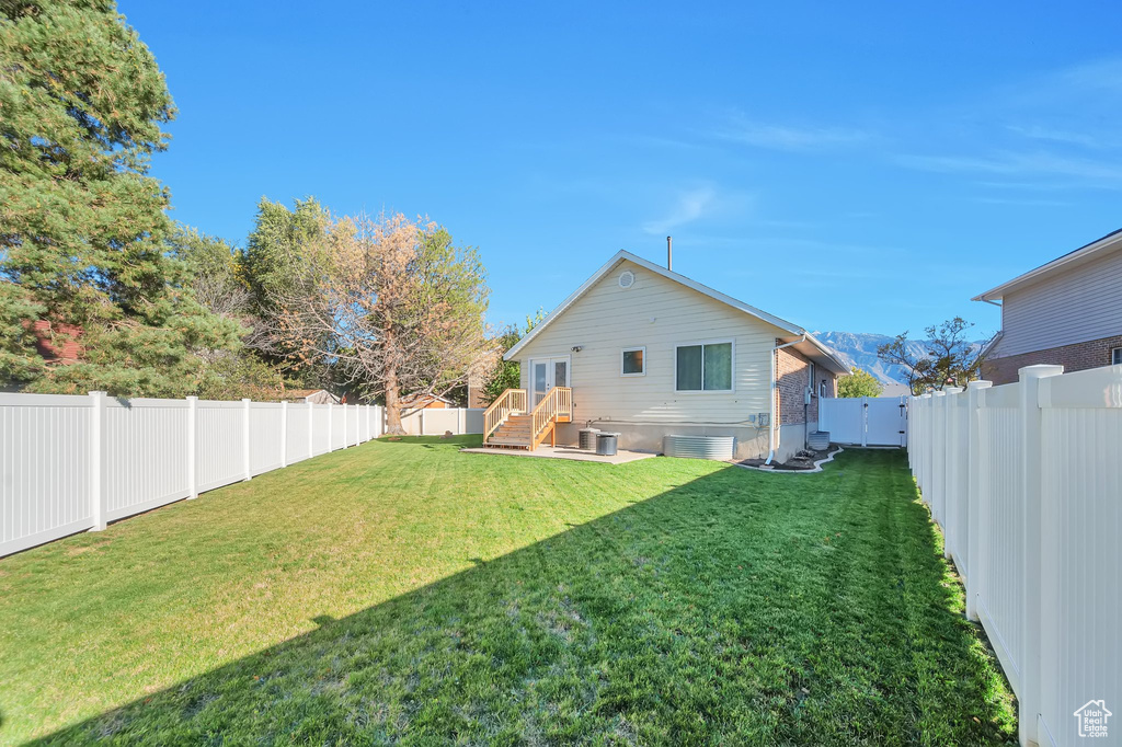 Back of house featuring a yard and central air condition unit