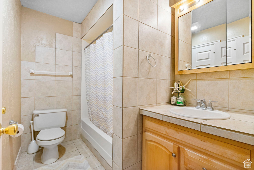 Full bathroom featuring vanity, toilet, and tile walls