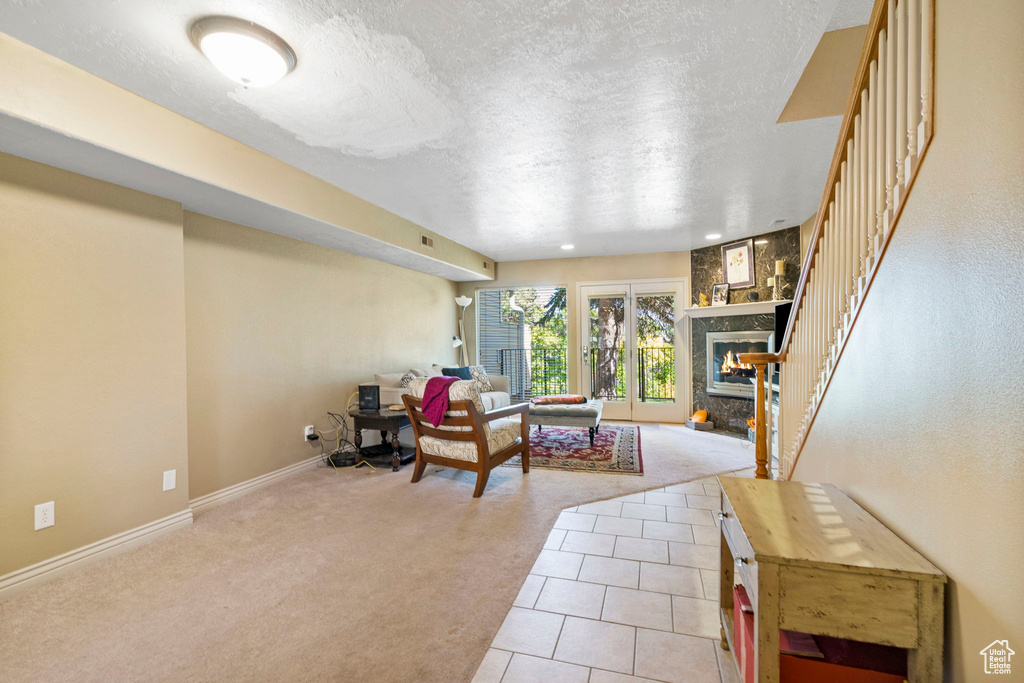 Living room featuring a textured ceiling, a fireplace, and light colored carpet