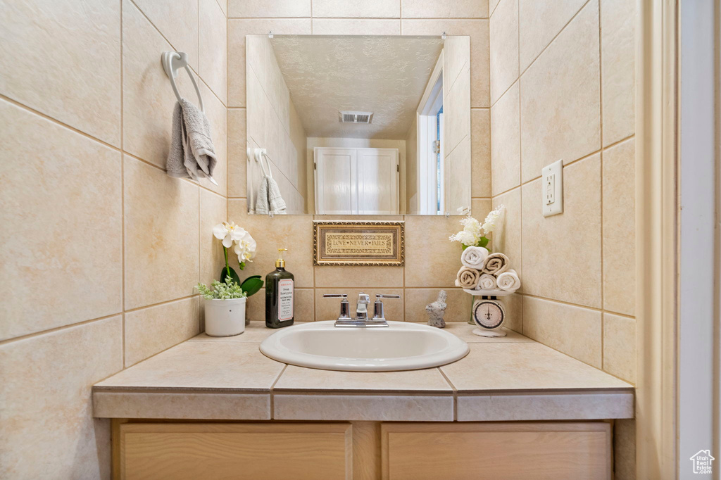 Bathroom with vanity and tile walls