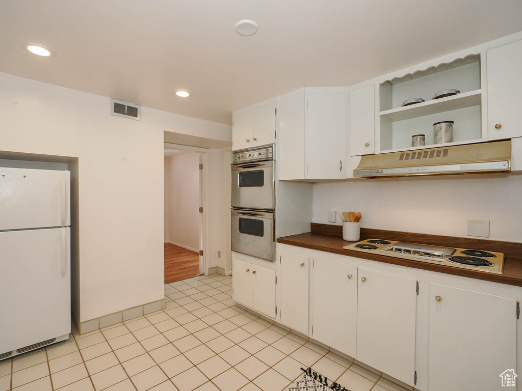 Kitchen featuring white appliances, white cabinetry, and light tile patterned floors