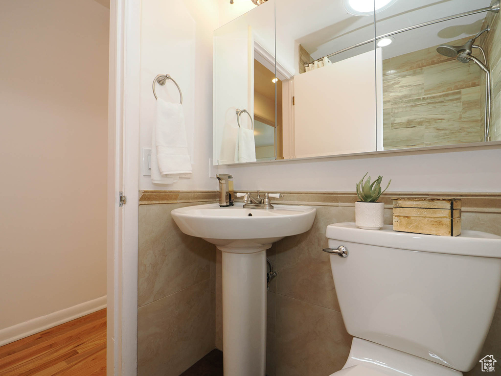 Bathroom featuring tile walls, a shower, hardwood / wood-style flooring, and toilet