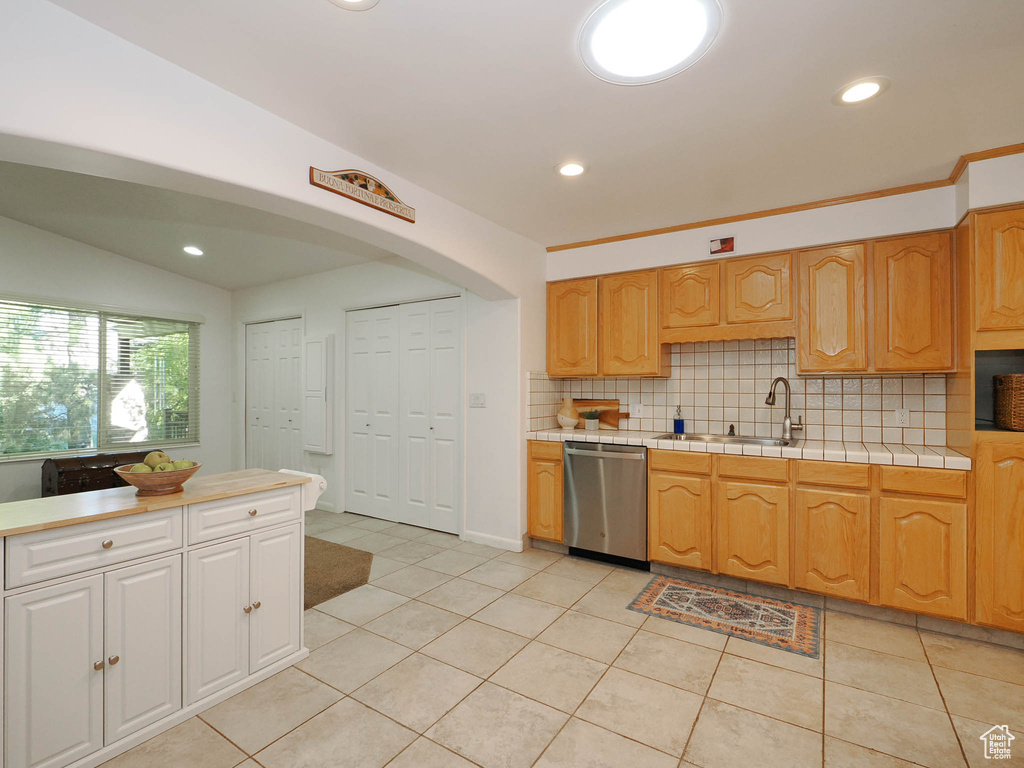 Kitchen featuring lofted ceiling, tasteful backsplash, dishwasher, light tile patterned flooring, and sink