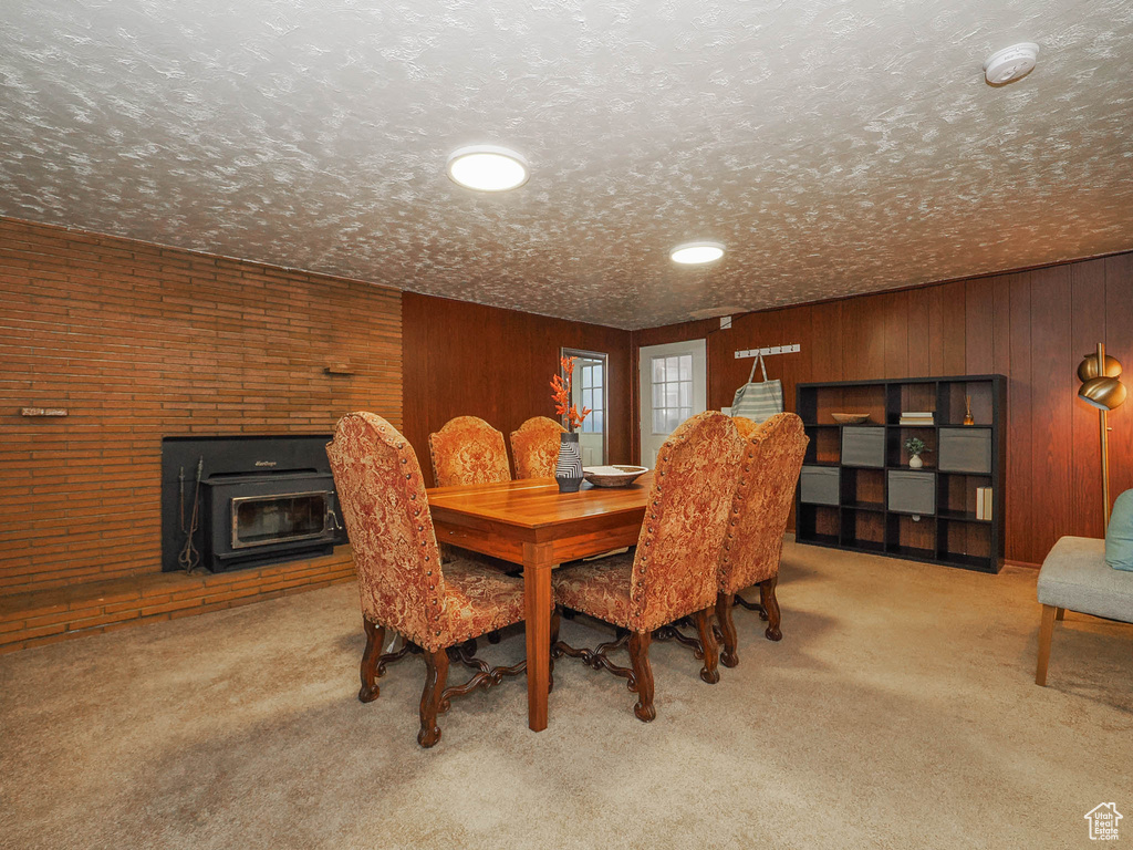 Dining space featuring a textured ceiling, carpet floors, and wooden walls