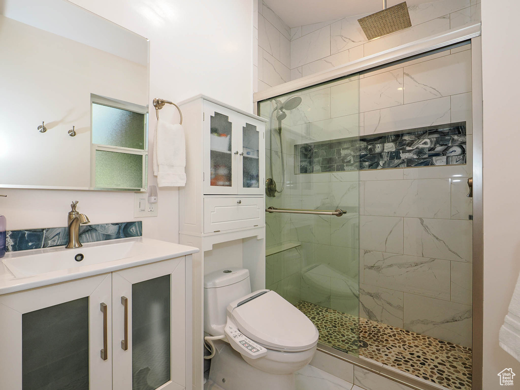 Bathroom with toilet, vanity, and a shower with door