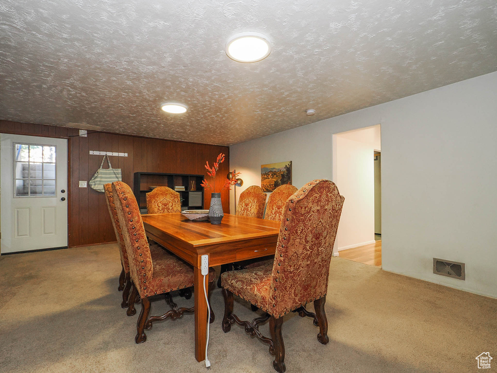 Carpeted dining area with a textured ceiling and wood walls