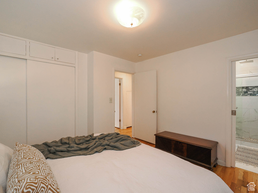 Bedroom with light hardwood / wood-style flooring, a closet, and connected bathroom