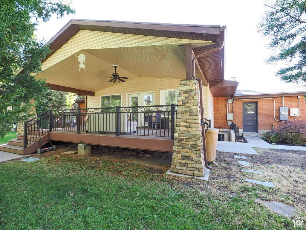 Back of house with a deck, a lawn, and ceiling fan