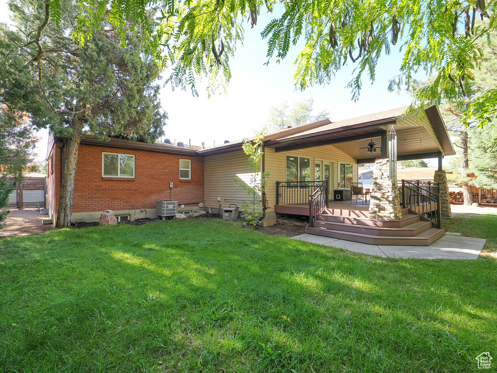 Rear view of house with a yard, a deck, and central air condition unit