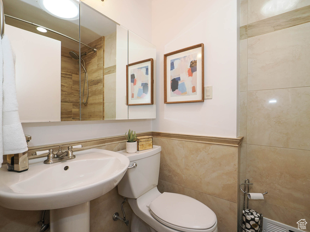 Bathroom featuring tile walls, tiled shower, and toilet