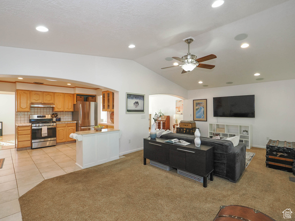 Carpeted living room featuring ceiling fan and vaulted ceiling