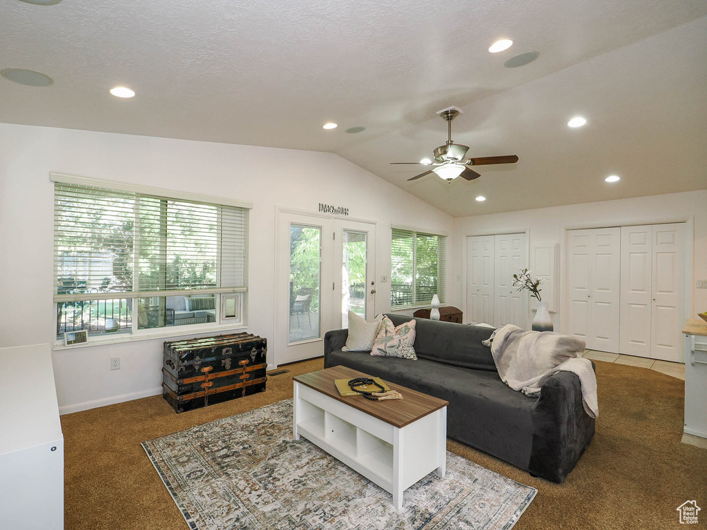 Living room featuring ceiling fan, a textured ceiling, vaulted ceiling, and dark colored carpet