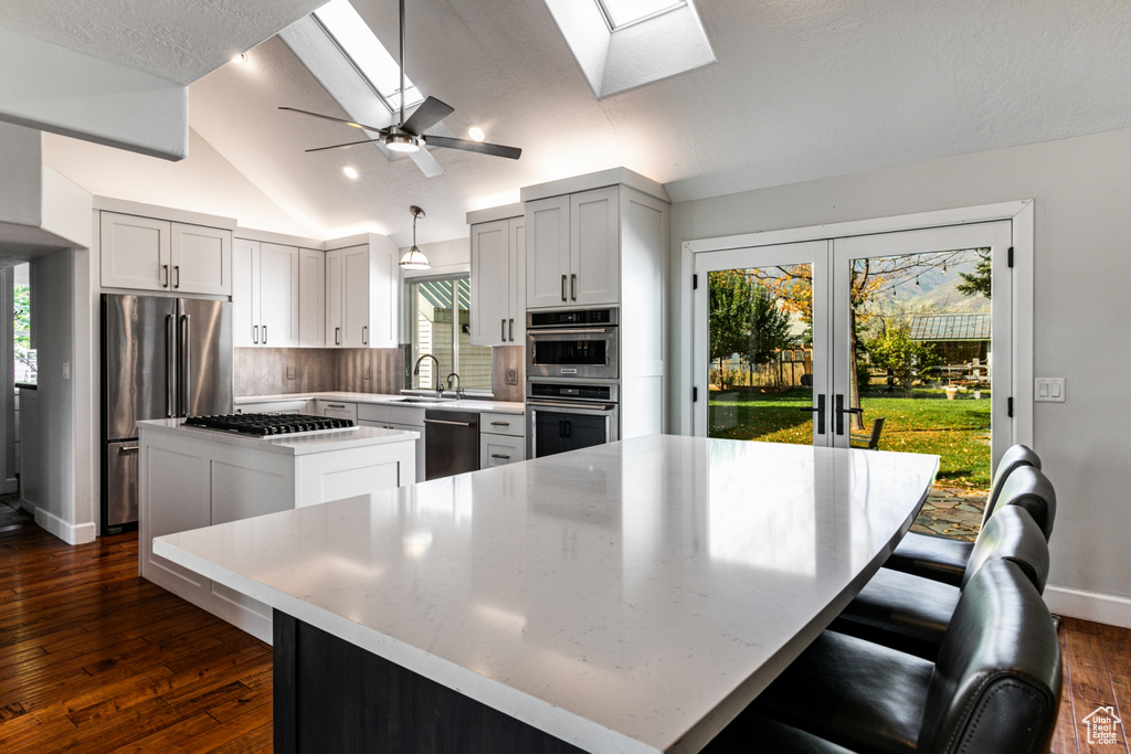 Kitchen with vaulted ceiling with skylight, a center island, and a wealth of natural light