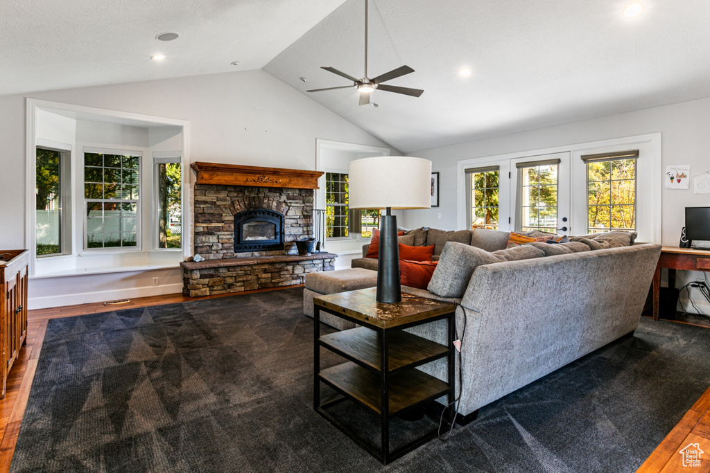 Living room with french doors, a stone fireplace, ceiling fan, lofted ceiling, and dark hardwood / wood-style floors