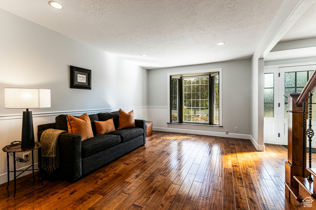 Living room with a textured ceiling, dark hardwood / wood-style flooring, and plenty of natural light