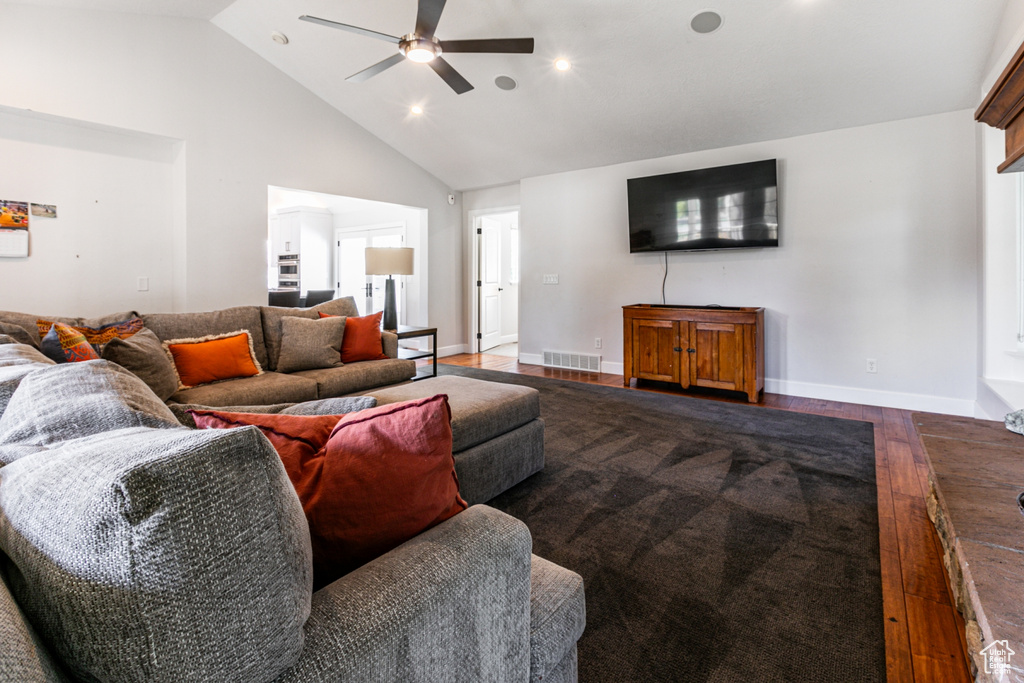 Living room with ceiling fan, high vaulted ceiling, and dark hardwood / wood-style flooring