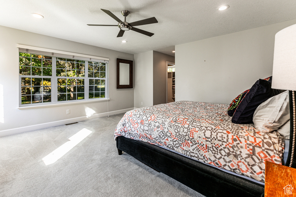 Bedroom featuring light carpet, a textured ceiling, and ceiling fan