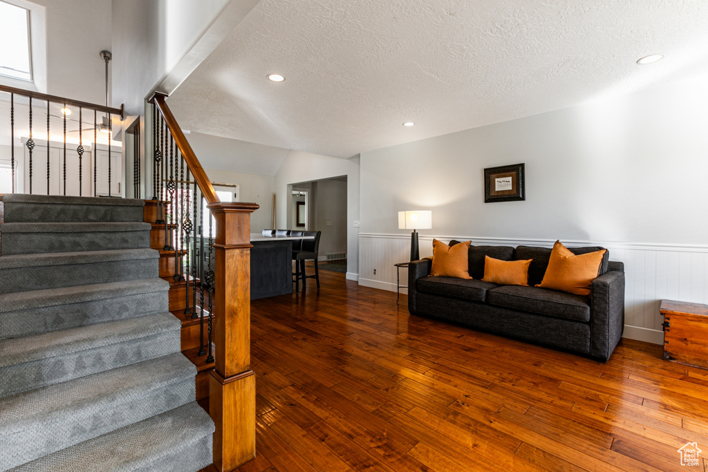 Living room featuring a textured ceiling, dark wood-type flooring, and vaulted ceiling