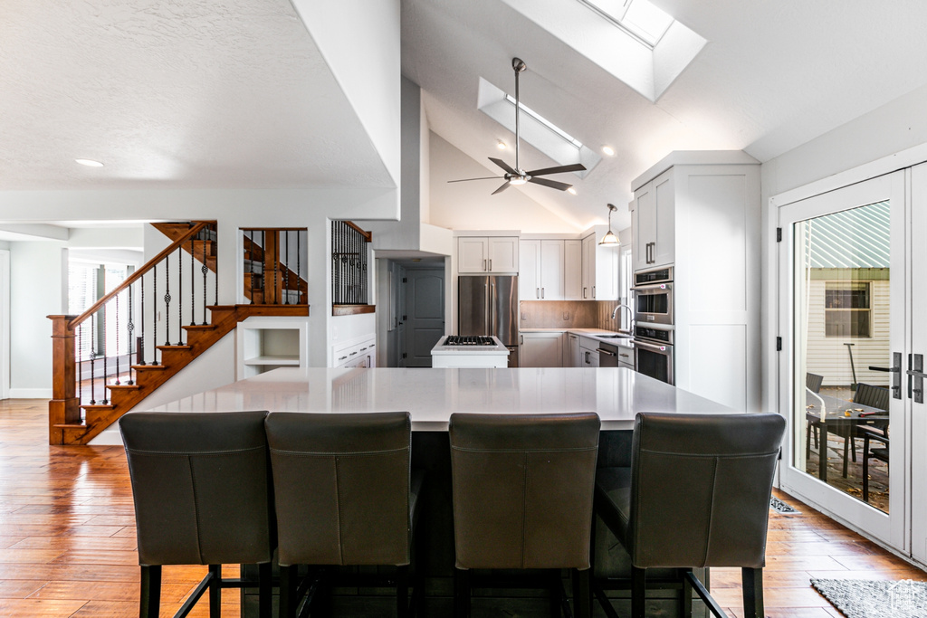 Kitchen featuring light hardwood / wood-style floors, a breakfast bar area, and white cabinets